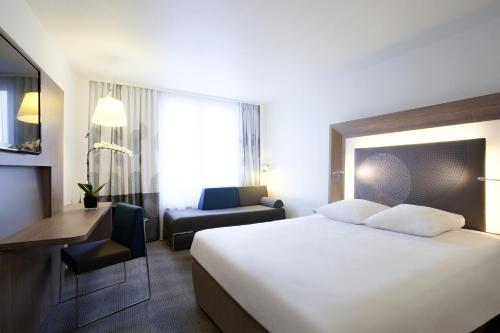 a hotel room with a large bed and a desk at Novotel Paris 17 in Paris