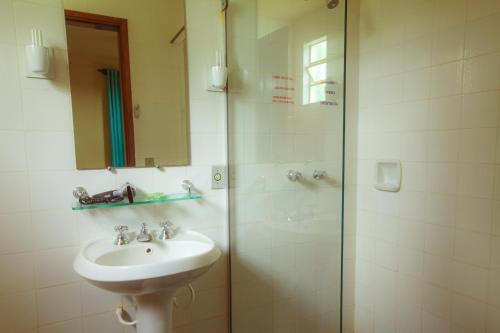 a bathroom with a sink and a shower at Pousada Penedo in Penedo