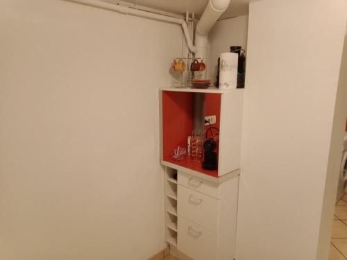 une cuisine avec des placards blancs et une étagère rouge dans l'établissement Terrace Flat Near The City Centre, à Brives-Charensac