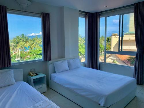 a bedroom with two beds and a large window at Oasis Nha Trang Hotel in Nha Trang