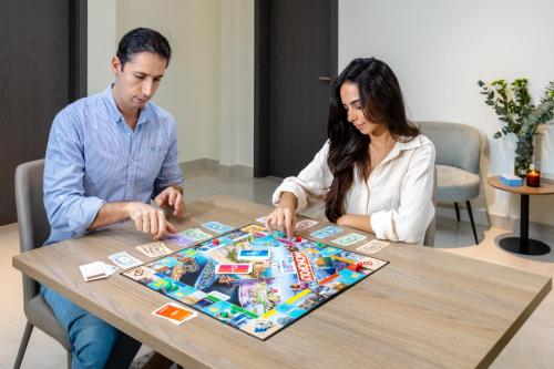 a man and woman playing a board game at a table at Unlock Metropolis Business Bay in Dubai