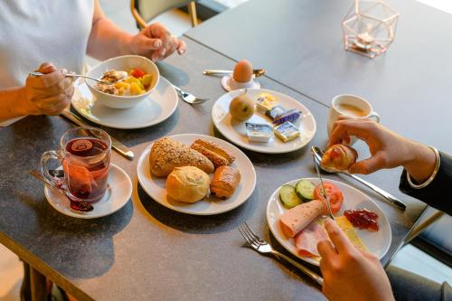 a table full of plates of food with people eating at ibis Hotel Friedrichshafen Airport Messe in Friedrichshafen