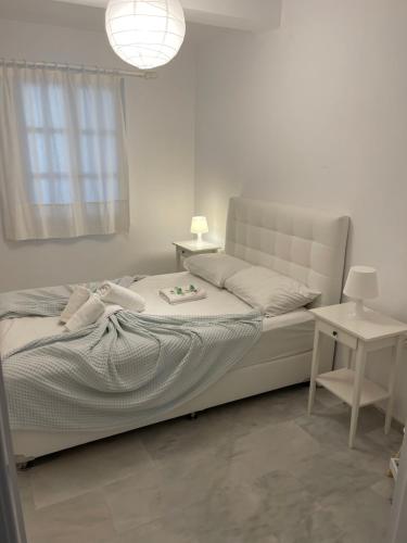 Dormitorio blanco con cama y mesa en Amedi Villas Tinos, en Pánormos