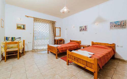 a bedroom with two beds and a table and chairs at Milios Studios in Megálon Choríon