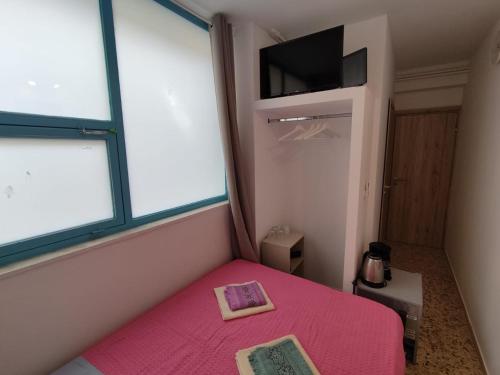 een kleine slaapkamer met een roze bed en een televisie bij PURE URBAN ACROPOLIS METRO PETRALONA in Athene