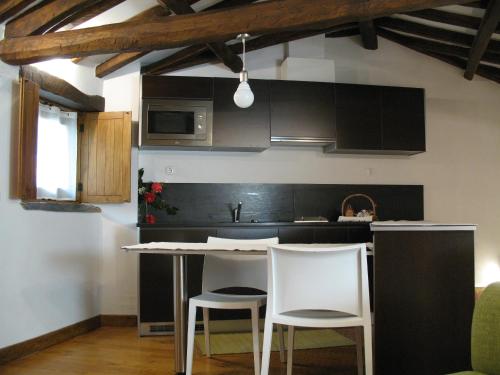 a kitchen with two white chairs and a kitchen island at Casa do Neveiro in Góis
