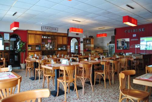 uma sala de jantar com mesas e cadeiras num restaurante em Hotel Les Voyageurs em Les Sables-dʼOlonne