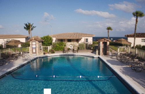 a large swimming pool with chairs and a house at Royal Flamingo Villas in Hillsboro Beach