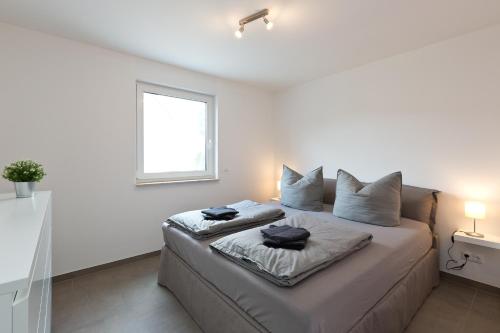 una camera bianca con un letto con due cuscini sopra di Apartment unter den Kiefern 93 a Röbel