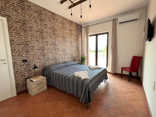 une chambre avec un lit et un mur de briques dans l'établissement Resort Amica, à Thurio