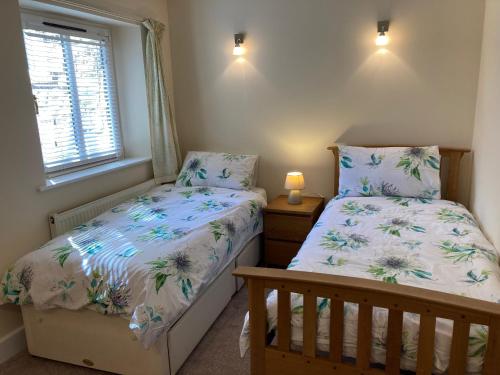 a bedroom with two twin beds and a window at 1 Coach House Mews - Matlock Bath in Matlock Bank