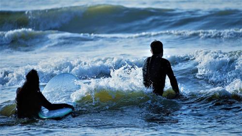 two people in the ocean with surfboards in the water at #1Leafy Place in Bentveld