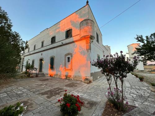 an orange and white building with flowers in front of it at Masseria Olga - Rural Coliving in Turi