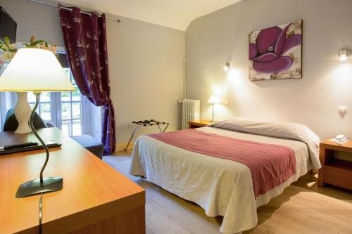 - une chambre avec un lit et un bureau avec une lampe dans l'établissement Le Vieux Moulin, à Hédé
