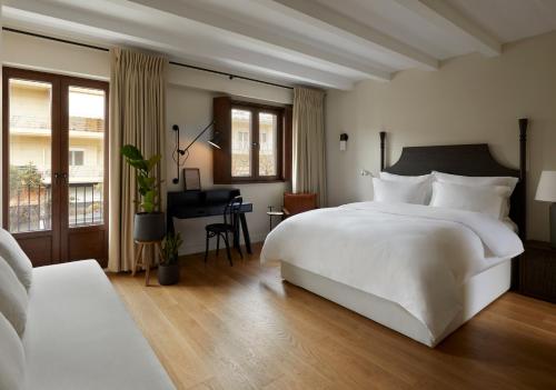 a bedroom with a large white bed and a desk at The Storyteller Boutique House in Kalabaka