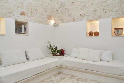 a white living room with white walls and white pillows at Trulleria Tagliente in Alberobello