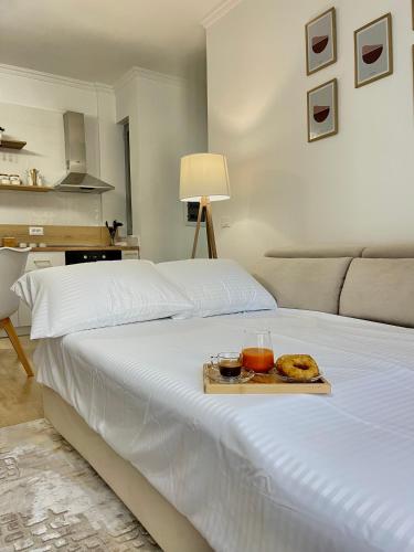 a white bed with a tray of food on it at KeSa Apartment in Korçë