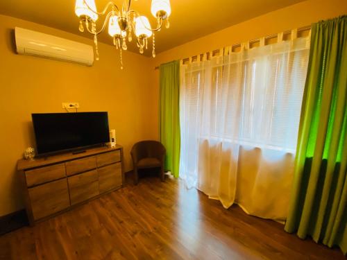 a living room with a television and green curtains at Gold Horse Vendégház in Szilvásvárad