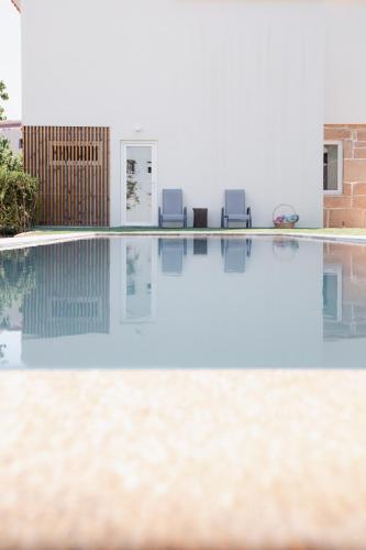 a swimming pool with two chairs and a house at Vila Real House in Vila Real