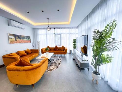 a living room with two couches and a tv at Olivia Chalet فلة أوليفيا in Al ‘Aqar