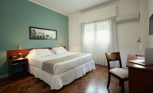 a bedroom with a large white bed and a desk at Gran Hotel Paysandú in Paysandú