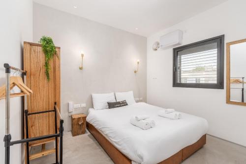 1 dormitorio con 1 cama con sábanas blancas y ventana en Trendy apartment next to Levinsky market en Tel Aviv