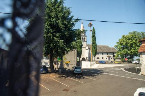 a street with a church and cars parked in a parking lot at Apartma Na skdnu in Dutovlje