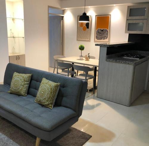uma sala de estar com um sofá azul e uma cozinha em LD House Flora em Cali
