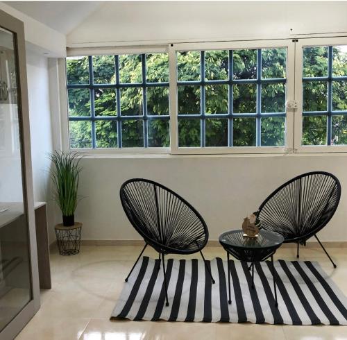 two chairs and a table in a room with windows at LD House Flora in Cali