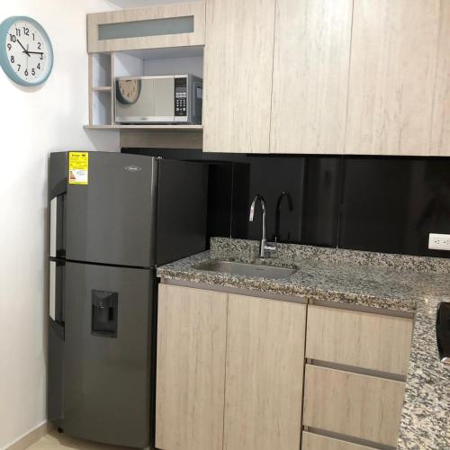 a kitchen with a black refrigerator and a microwave at LD House Flora in Cali