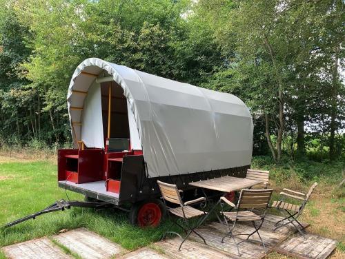 a white trailer with chairs and a table in a field at Huifkar in landelijke omgeving De Mersken 9 Ureterp in Ureterp