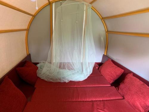 ein rotes Sofa in einem Zimmer mit Fenster in der Unterkunft Huifkar in landelijke omgeving in Ureterp