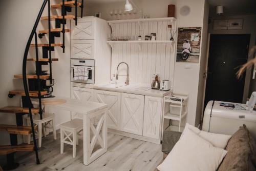 cocina con armarios blancos, fregadero y mesa en Lovely apartment Nadolnik, en Poznan