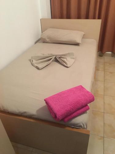 a bed with a bow tie and a pink towel at "Frogs House" Hotel & Restorant Slow Food in Lushnjë