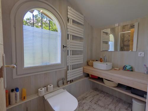 une salle de bain avec toilettes, lavabo et fenêtre dans l'établissement Villa 'Andercool' avec piscine utilisable en toutes saisons, à Andernos-les-Bains