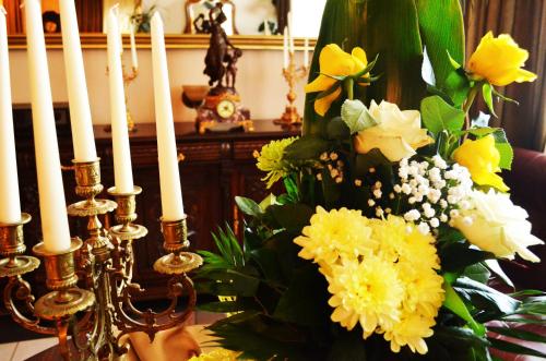 a table topped with white candles and yellow flowers at Pensiunea Magura in Baia Mare