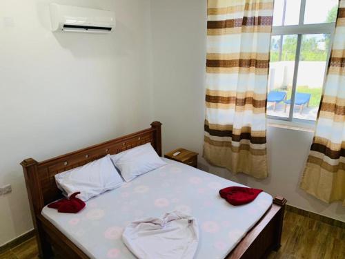 a bedroom with a bed with red pillows and a window at Villa Liam B&B Kiwengwa Zanzibar in Kumba Urembo