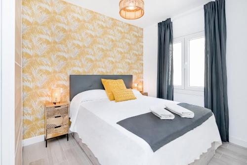 um quarto com uma grande cama branca com almofadas amarelas em San Jorge em Málaga