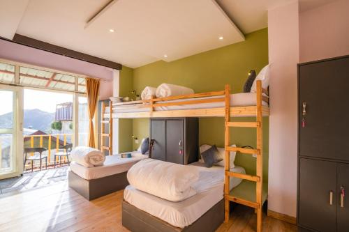 a room with two bunk beds and a balcony at Zostel Banikhet (Dalhousie) in Dalhousie