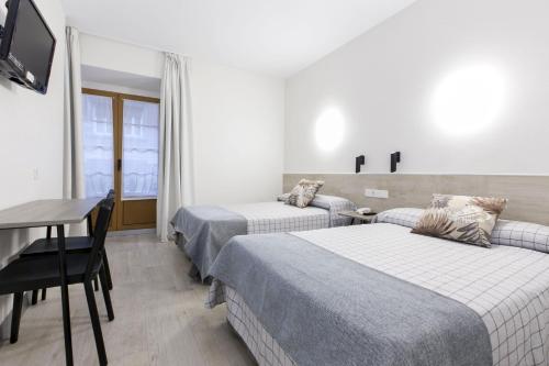 a hotel room with two beds and a table at Hostal Castilla II Puerta del Sol in Madrid