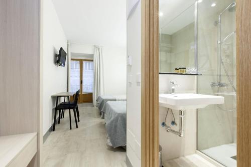 a bathroom with a sink and a shower and a bed at Hostal Castilla II Puerta del Sol in Madrid