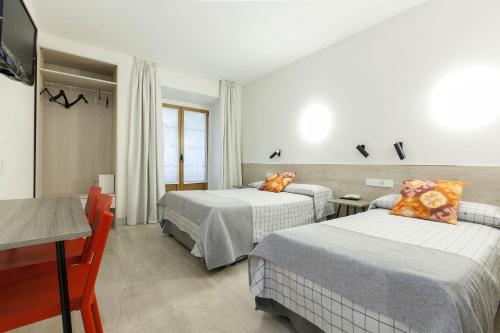 a hotel room with two beds and a television at Hostal Castilla II Puerta del Sol in Madrid