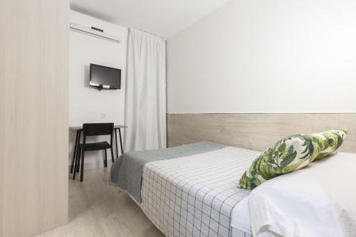a hotel room with two beds and a table and a television at Hostal Castilla II Puerta del Sol in Madrid