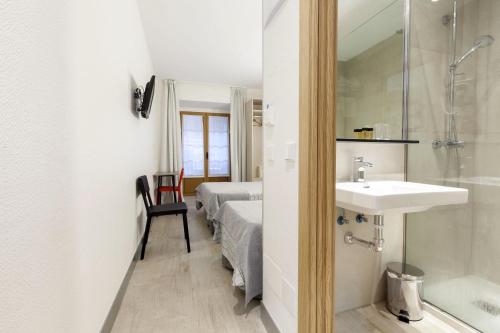 a bathroom with a sink and a shower and a bed at Hostal Castilla II Puerta del Sol in Madrid
