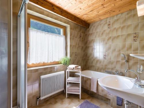 een badkamer met een bad, een wastafel en een raam bij Apartments Fleidl in Zell am Ziller
