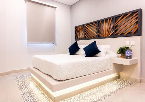 a bedroom with a large white bed with blue pillows at The Garden by DOT Suites in Santa Marta