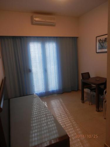 a room with a window with blue curtains and a table at Glaros Hotel Apartment in Agia Galini