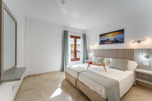 Un dormitorio con una gran cama blanca y una ventana en Klayman Olivina Aparthotel, en Los Cristianos