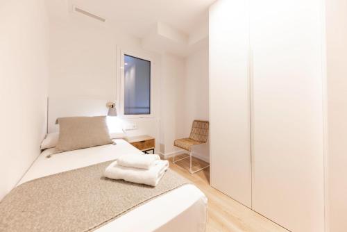 1 dormitorio blanco con 1 cama y 1 silla en Bravissimo Falcó, 3 bedrooms and balcony, en Girona