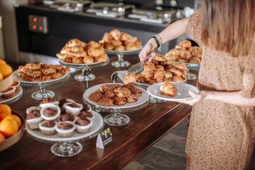a woman holding a plate in front of a buffet of pastries at Le Ali Del Frassino in Peschiera del Garda